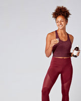 Woman in athletic wear holding a bottle of Multi Strain Biotic and a glass